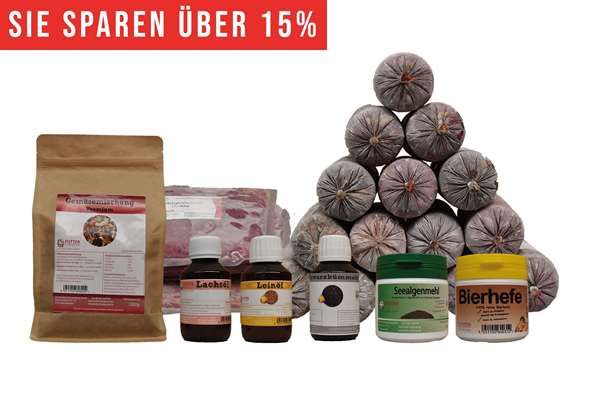 Ein BARF-Paket mit pyramidenförmig gestapelten Frostfleischrollen im Kunstdarm. Davor eine Papiertüte, zwei flache Beutel und sechs Ergänzungsprodukte. Oben links ein rotes Banner mit weißer Aufschrift „Sie sparen über 10 %“.