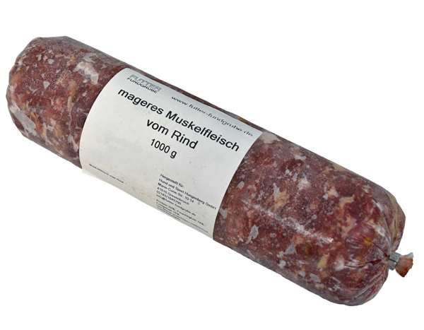Eine vakuumverpackte Wurstrolle, verpackt in einem nicht essbaren Kunstdarm, liegt quer im Bild. Auf dem weißen Etikett steht „mageres Muskelfleisch vom Rind – 1000 g“. Die Rolle enthält fettarmes, rohes Rindermuskelfleisch zur Tierfütterung.