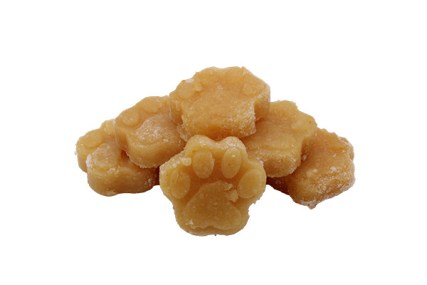Mehrere gefrorene, orangefarbene Pfötchen aus püriertem Apfel, leicht übereinandergestapelt.